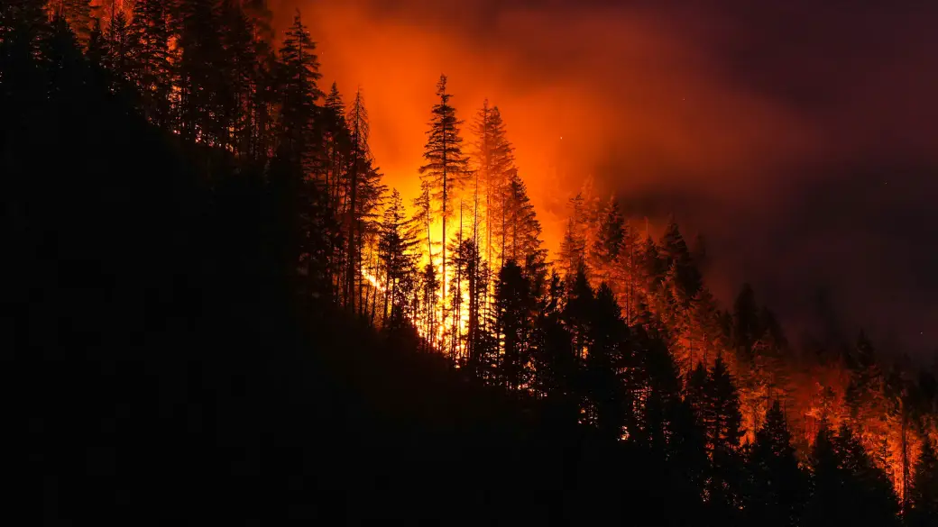 Helicopter dropping water on active BC wildfire